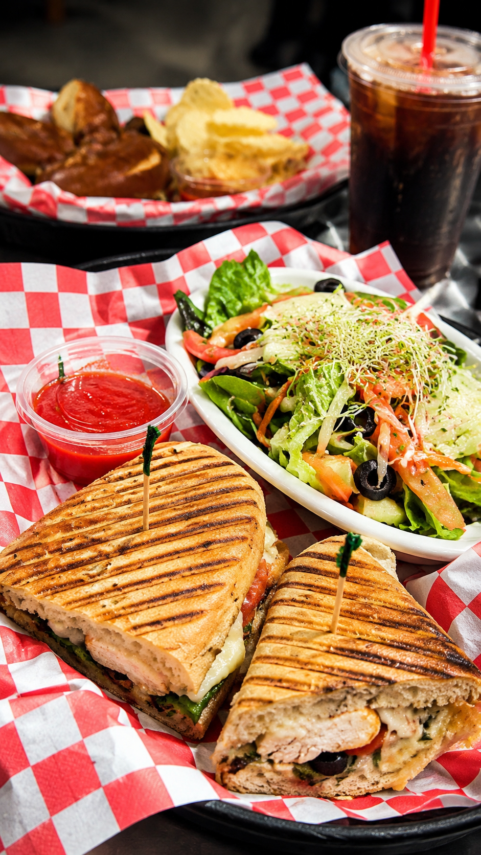 CJ's $15 lunch combo — grilled panini, fresh salad, chips, marinara dip, and iced fountain drink on red checkered diner paper
